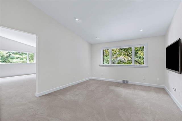 carpeted spare room featuring lofted ceiling and plenty of natural light