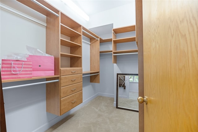 walk in closet featuring light carpet and built in desk