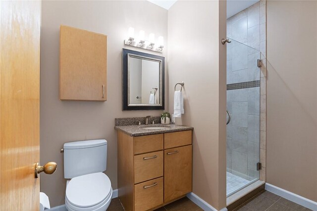 bathroom with a shower with shower door, vanity, tile patterned flooring, and toilet