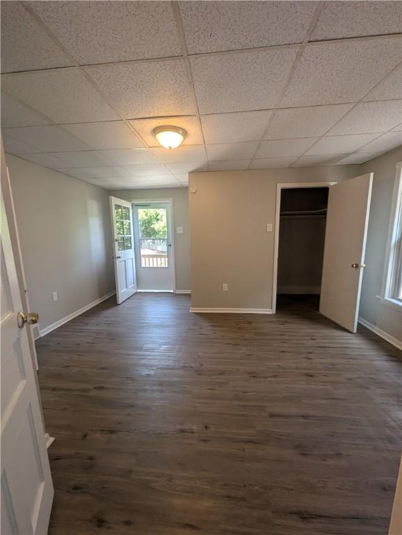 unfurnished bedroom with dark hardwood / wood-style floors, a closet, and a drop ceiling