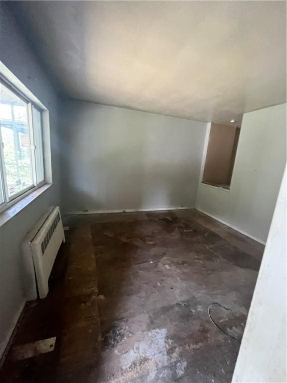 unfurnished room with radiator and vaulted ceiling