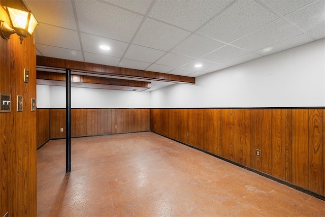 basement with wooden walls and a paneled ceiling