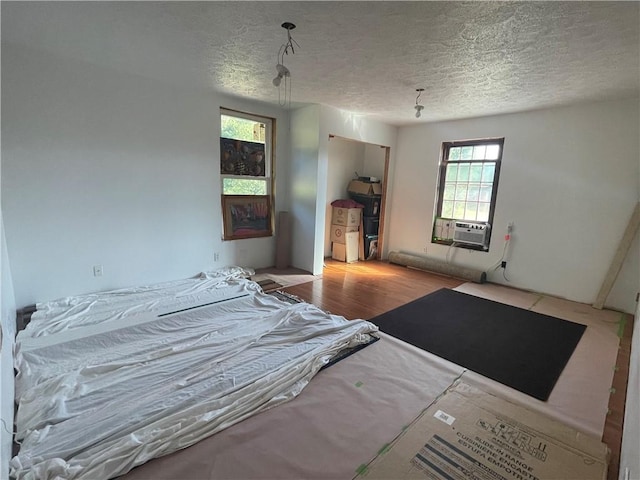 bedroom featuring wood finished floors, a textured ceiling, and cooling unit