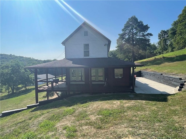 rear view of property with a lawn, roof with shingles, and a patio