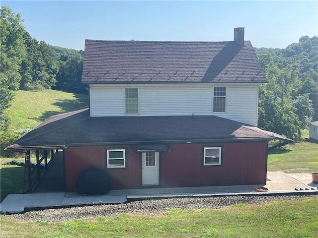 back of house with a patio area, a shingled roof, and a chimney
