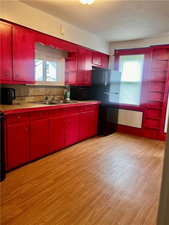 kitchen with light wood-style floors, red cabinets, backsplash, and open shelves