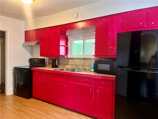 kitchen with sink, light wood-type flooring, tasteful backsplash, and black appliances