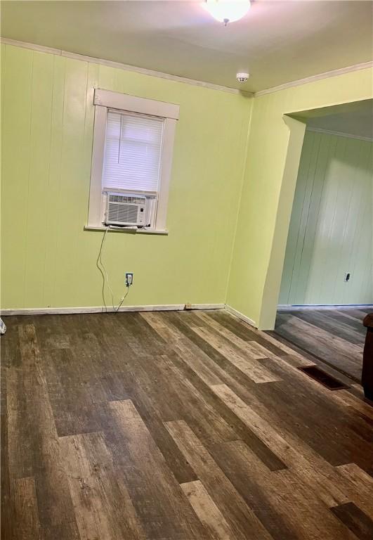 empty room featuring dark wood-type flooring, cooling unit, and crown molding