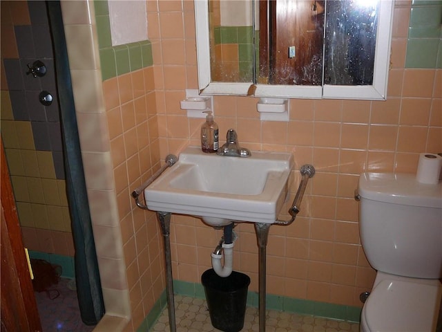 bathroom featuring sink, tile walls, and toilet