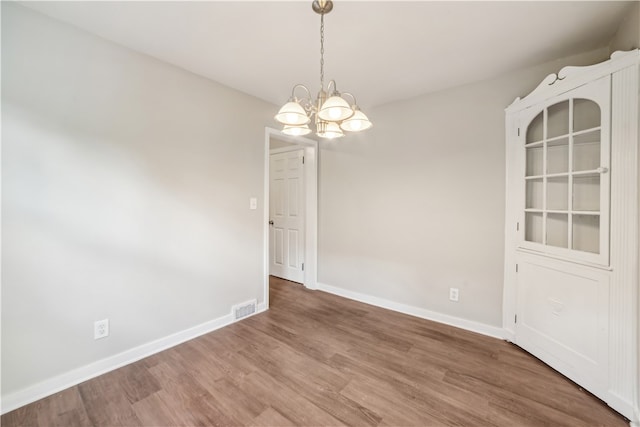 unfurnished dining area with a notable chandelier and hardwood / wood-style flooring