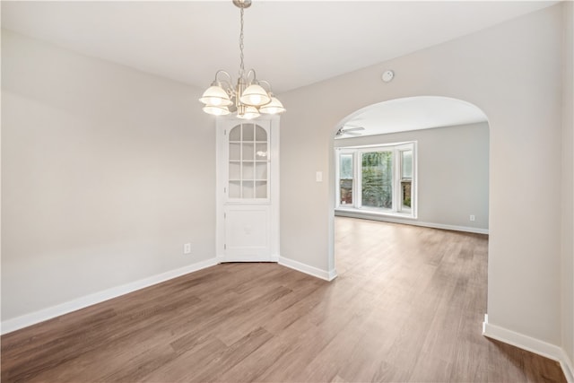 empty room featuring an inviting chandelier and hardwood / wood-style floors