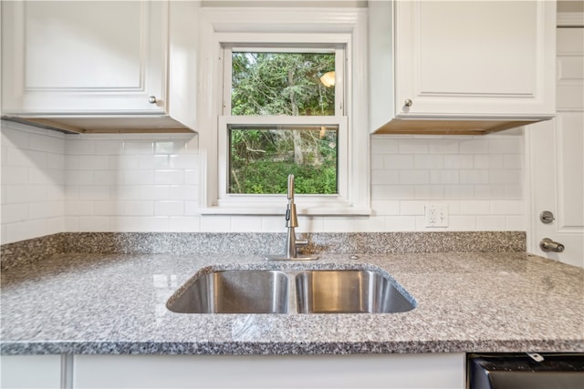 kitchen with sink, light stone countertops, white cabinets, and backsplash