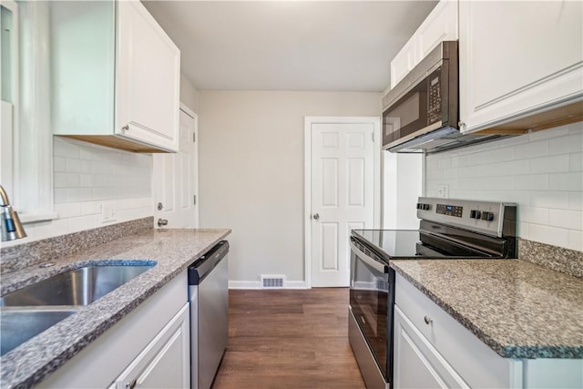 kitchen with dark wood-type flooring, stainless steel appliances, light stone counters, sink, and white cabinetry