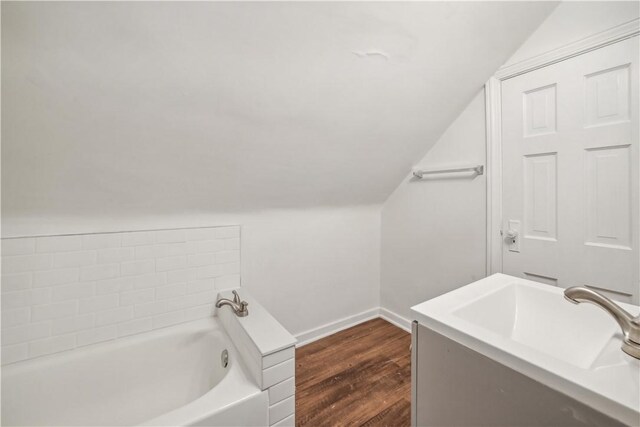 bathroom with sink, wood-type flooring, a washtub, and lofted ceiling