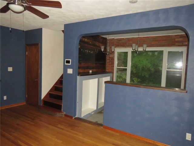 spare room with ceiling fan with notable chandelier, wood-type flooring, and a textured ceiling