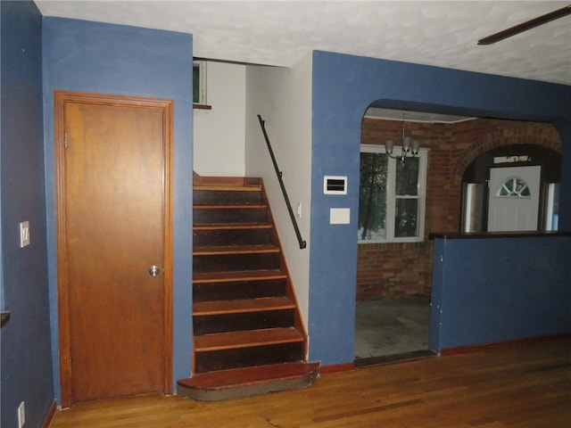 stairs featuring a textured ceiling, brick wall, and hardwood / wood-style flooring