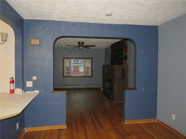 unfurnished dining area featuring a textured ceiling, dark wood-type flooring, ceiling fan, and a fireplace