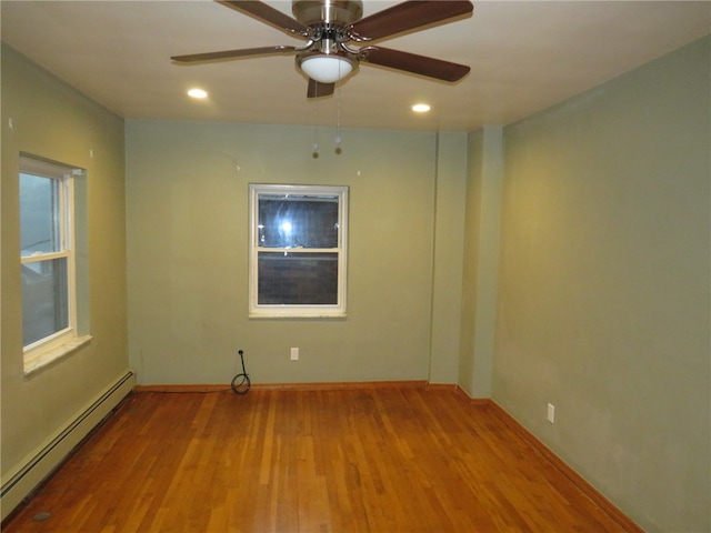 unfurnished room with a baseboard heating unit, hardwood / wood-style floors, and ceiling fan