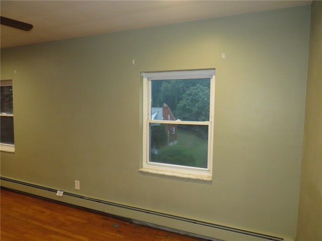 unfurnished room with hardwood / wood-style floors and a baseboard radiator