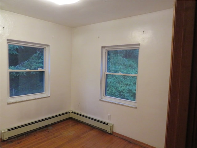 empty room featuring a baseboard heating unit and wood-type flooring