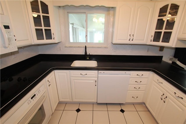 kitchen with white appliances, white cabinetry, light tile patterned floors, and sink