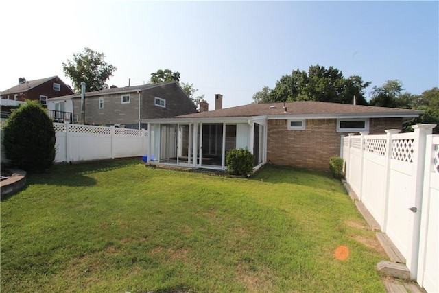 rear view of house with a yard and a sunroom