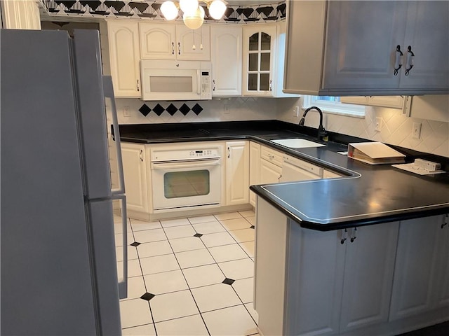 kitchen with white appliances, light tile patterned flooring, white cabinetry, and sink