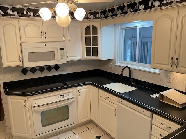 kitchen featuring sink, white cabinetry, white appliances, light tile patterned floors, and backsplash