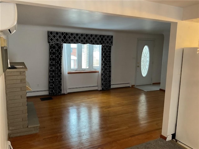 foyer featuring a wall unit AC, wood-type flooring, and baseboard heating