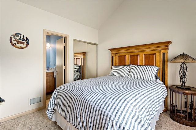 carpeted bedroom featuring ensuite bathroom and lofted ceiling