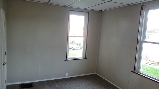 unfurnished room featuring carpet floors, a paneled ceiling, and a wealth of natural light