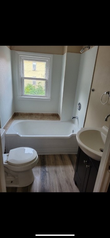 bathroom featuring a bath, vanity, toilet, and hardwood / wood-style flooring