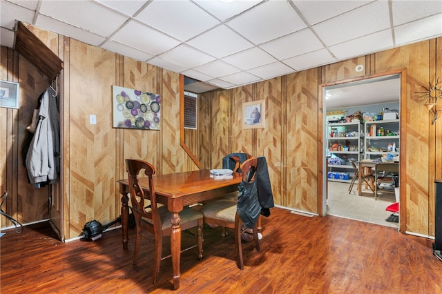 tiled dining area featuring wood walls and a drop ceiling