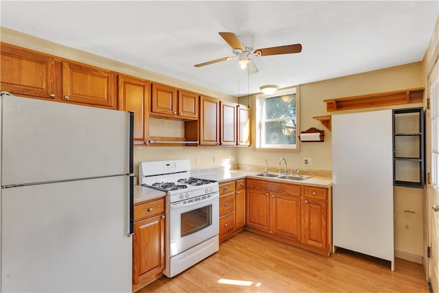 kitchen featuring light wood-type flooring, white appliances, ceiling fan, and sink