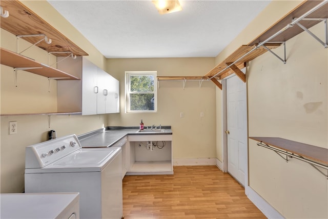 clothes washing area with cabinets, light hardwood / wood-style flooring, sink, and independent washer and dryer