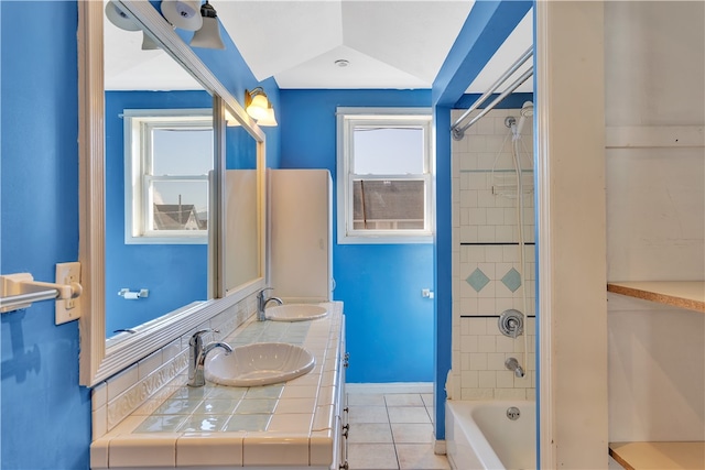 bathroom featuring tiled shower / bath combo, vanity, vaulted ceiling, and tile patterned floors