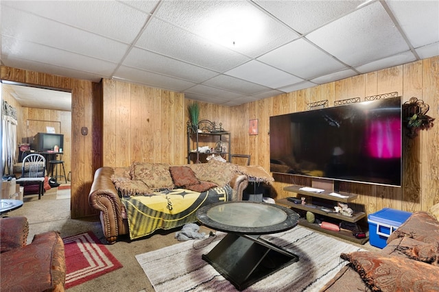 living room with wood walls, carpet floors, and a paneled ceiling