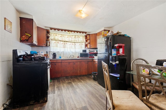 kitchen featuring black appliances, hardwood / wood-style floors, and sink