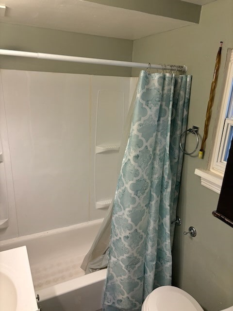 bathroom featuring toilet and shower / bath combination with curtain