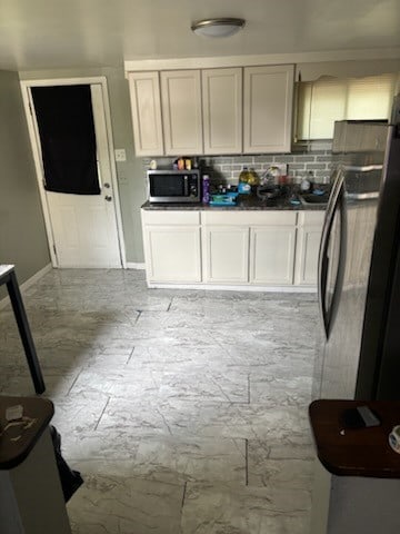 kitchen featuring cream cabinets, light tile patterned floors, backsplash, and stainless steel appliances