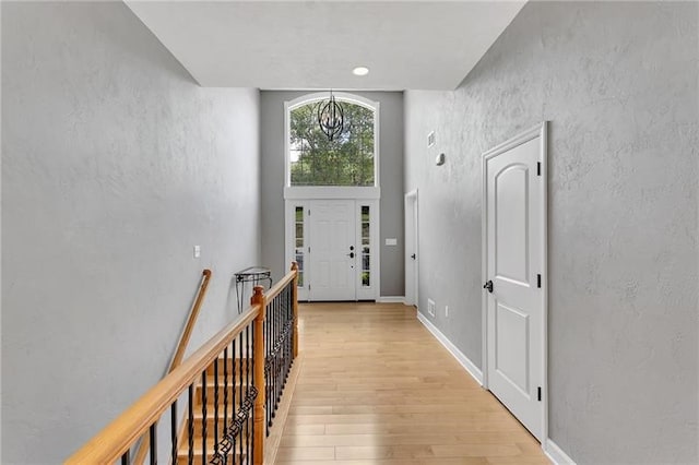 interior space featuring light wood-type flooring, a towering ceiling, baseboards, and a textured wall