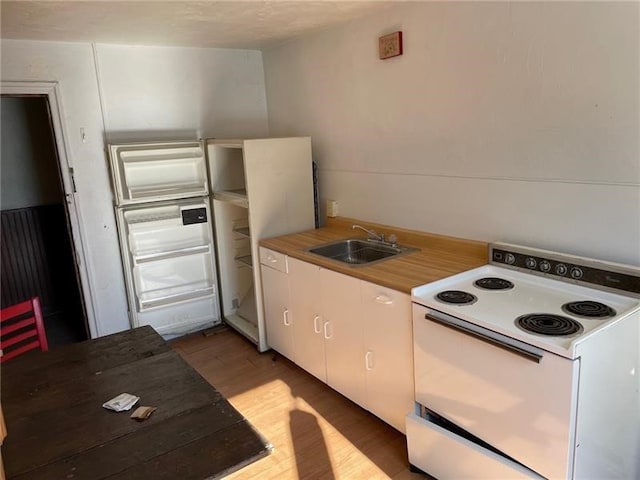 kitchen featuring sink, electric stove, light wood-type flooring, and white cabinetry