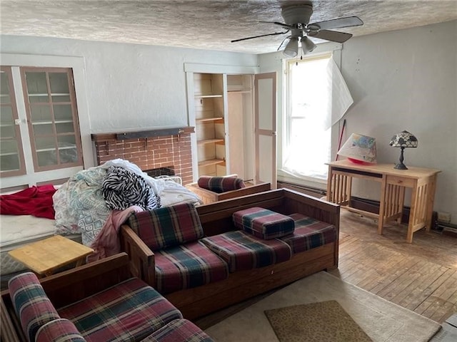 living room featuring a fireplace, a textured ceiling, hardwood / wood-style flooring, and ceiling fan