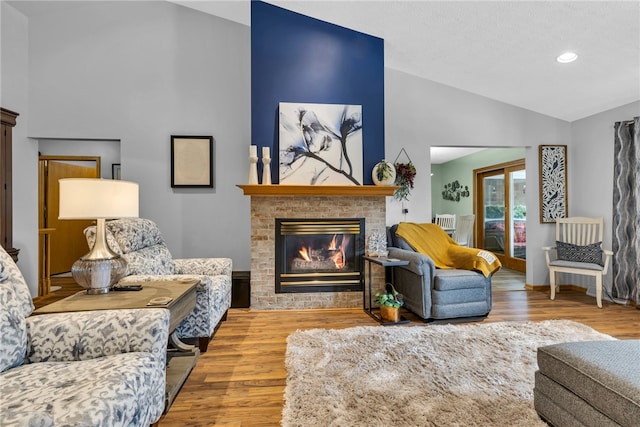 living room featuring a brick fireplace, hardwood / wood-style flooring, and high vaulted ceiling