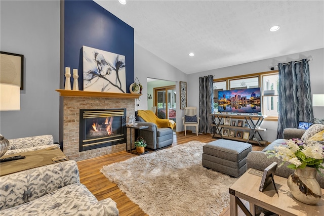 living room featuring high vaulted ceiling, a fireplace, and hardwood / wood-style flooring