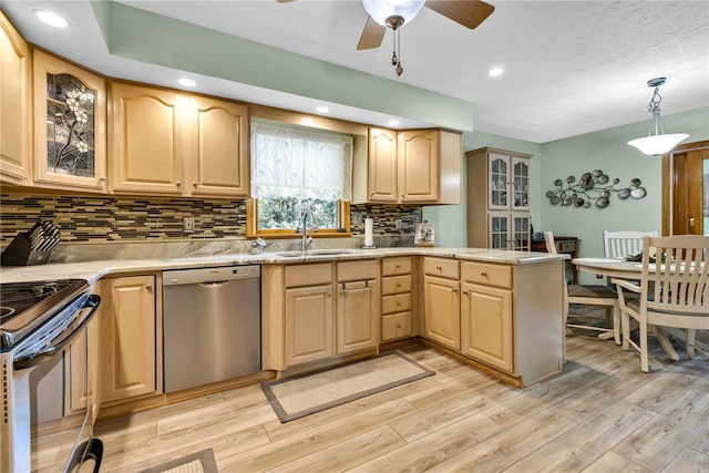 kitchen with kitchen peninsula, stainless steel dishwasher, hanging light fixtures, decorative backsplash, and sink