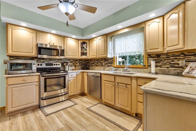 kitchen with appliances with stainless steel finishes, backsplash, and light brown cabinets