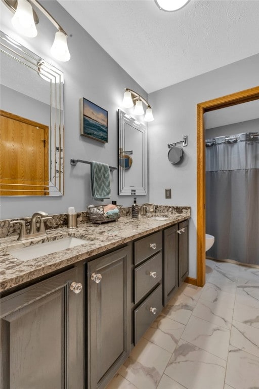 bathroom featuring double vanity, tile patterned flooring, toilet, and a textured ceiling