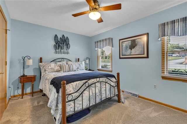 bedroom featuring a textured ceiling, multiple windows, carpet flooring, and ceiling fan