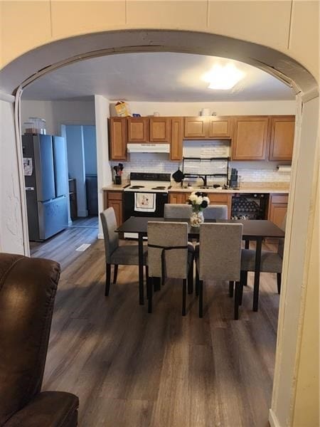 kitchen with stainless steel fridge, dark hardwood / wood-style flooring, white range with electric cooktop, and decorative backsplash